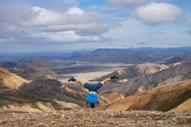 Randonneur debout sur sa main dans la vallée de Landmannalaugar. Islande. Montagnes colorées sur le sentier de randonnée de Laugavegur. La combinaison de couches de roches multicolores, de minéraux, d'herbe et de mousse.