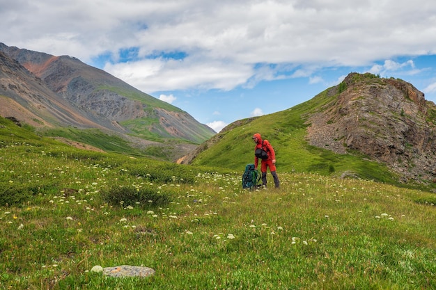 Un randonneur fatigué met un gros sac à dos lourd. Temps de repos lors d'une randonnée, une aire de repos. Mode de vie de voyage, piste dure de randonnée.