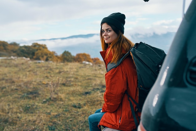 Randonneur femme dans des vêtements chauds au repos à l'automne dans les montagnes près de la voiture