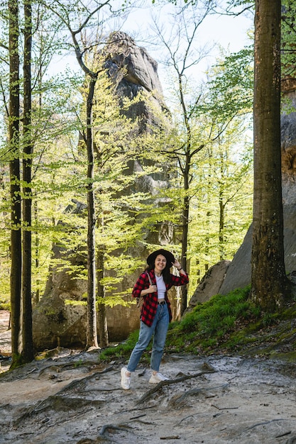 Randonneur femme avec sac à dos marchant par sentier forestier