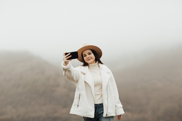 Randonneur fille prenant un selfie sur fond de beaux paysages de la nature à l'aide de téléphone mobile.