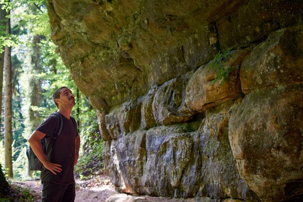 Un randonneur hispanique adulte avec un sac à dos regardant les murs d'une grotte dans une forêt
