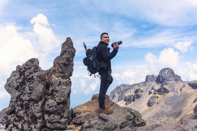 Un randonneur hispanique souriant avec un appareil photo professionnel sur un appareil photo au sommet du volcan Iztaccihuatl