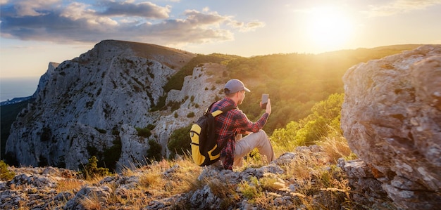 Randonneur d'homme fort prenant la photo avec le téléphone intelligent au sommet de la montagne