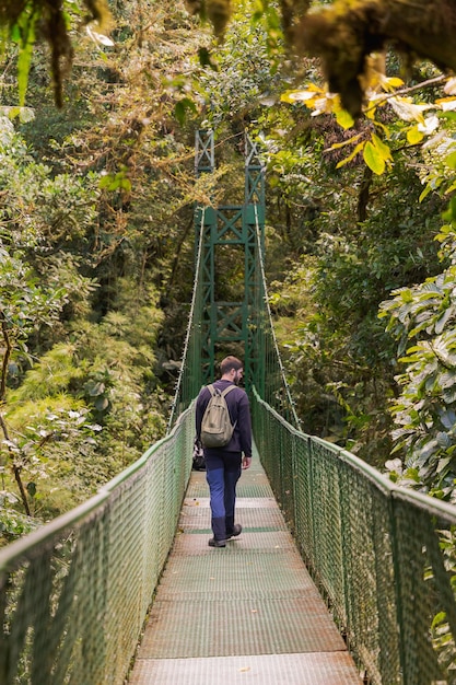 Randonneur homme marchant sur un pont suspendu dans la jungle