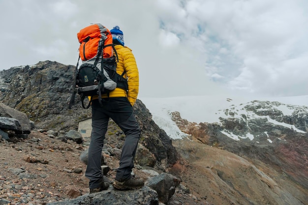 Randonneur homme avec sac à dos devant une montagne