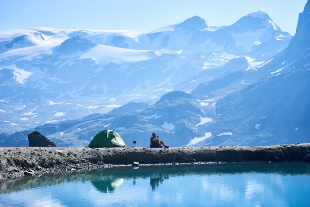 Randonneur homme se reposant près de la tente du camp dans les montagnes
