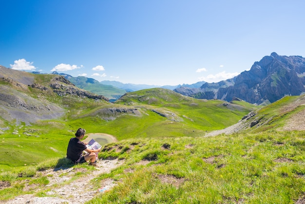 Randonneur en lisant une carte de trekking tout en se reposant à la montagne panoramique