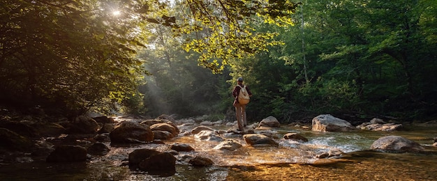 Randonneur mâle heureux trekking à l'extérieur dans la forêt près de la rivière