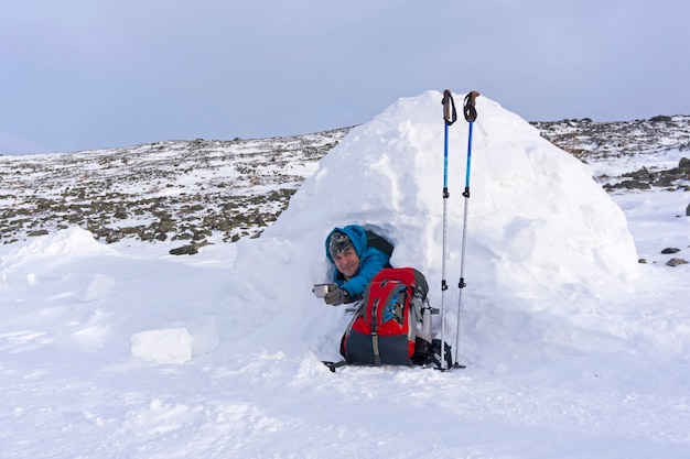 Randonneur Offre Une Tasse De Thé Tout En étant Assis Dans Un Petit Igloo Hutte Enneigée