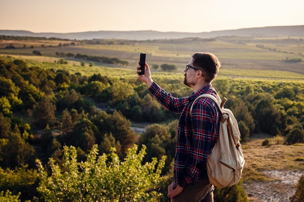 Randonneur prenant la photo du beau paysage de montagne avec le téléphone portable