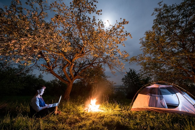 Randonneur près de feu de camp et tente touristique la nuit