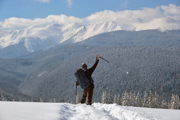 Randonneur réussi avec sac à dos marchant sur une colline de montagne enneigée par une froide journée d'hiver.