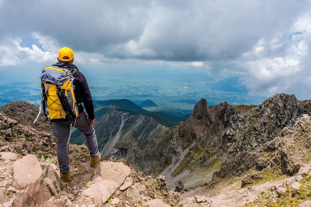 Un randonneur avec un sac à dos debout au sommet de la montagne