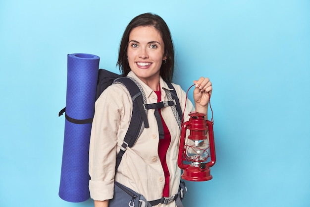 Randonneur avec sac à dos lanterne et tapis sur bleu