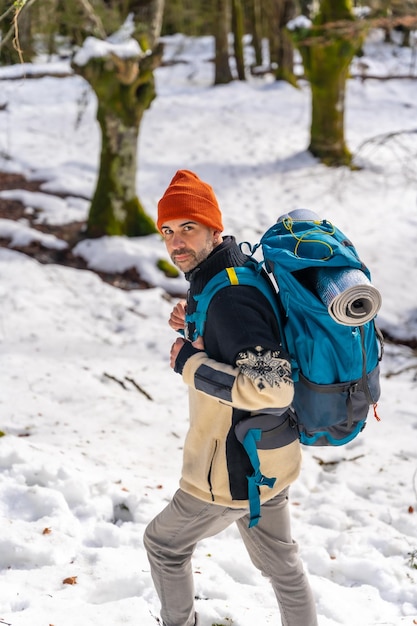 Randonneur avec sac à dos lors d'aventures hivernales de trekking dans la neige dans une forêt de hêtres