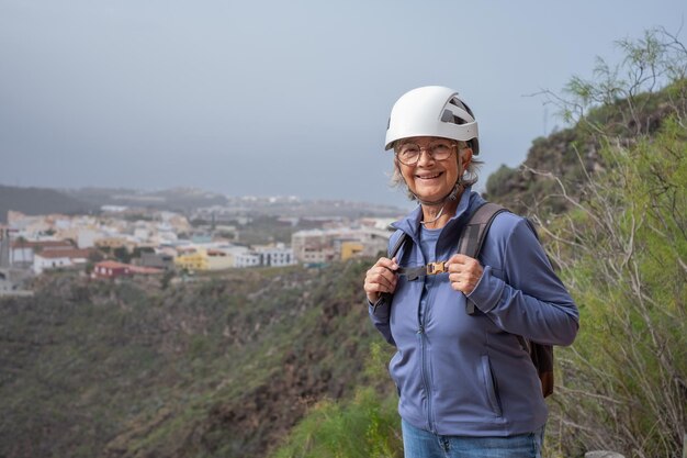 Randonneur senior femme avec sac à dos et casque profitant d'une journée de trekking en montagne Touriste actif