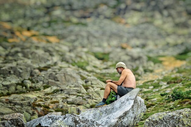Randonneur solitaire assis sur des rochers dans les montagnes.