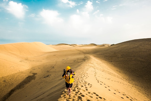 Randonneur solitaire aventurier dans le désert de sable avec une infinité - des dunes de sable partout pour des vacances sauvages alternatives pour les gens qui aiment le mode de vie heureux dans les espaces extérieurs - la joie du concept de voyage