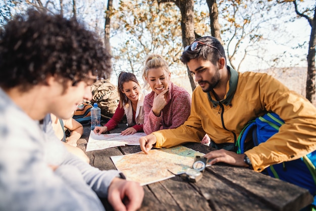 Photo randonneurs assis sur le banc à la table dans les bois et en regardant la carte