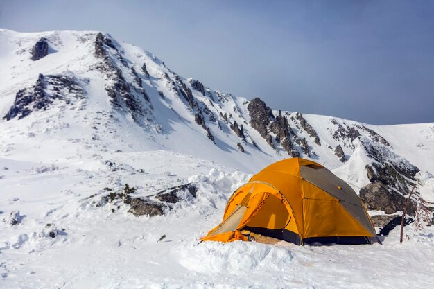 Les randonneurs installent une tente orange dans les montagnes d'hiver Alpinism sport