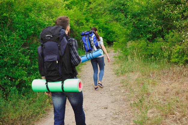 Randonneurs de jeune couple en forêt. sport homme et femme avec des sacs à dos sur route dans la nature.