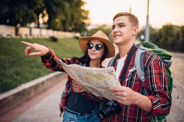 Randonneurs avec sacs à dos à la recherche des attractions de la ville sur la carte, excursion en ville touristique. Randonnée d'été. Randonnée aventure de jeune homme et femme