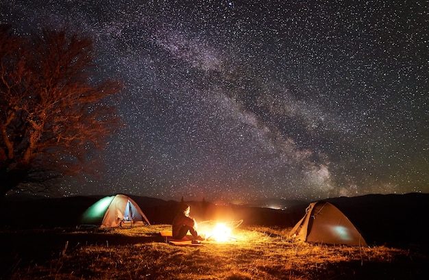 Les randonneurs se reposant près d'un feu de camp sous un ciel étoilé