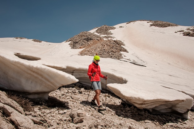 Randonneuse avec des cannes parmi les mottes de neige