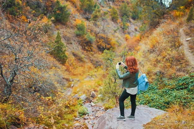 Randonneuse prenant selfie dans la forêt des montagnes. Touriste avec un sac à dos admire le rocher de la montagne.