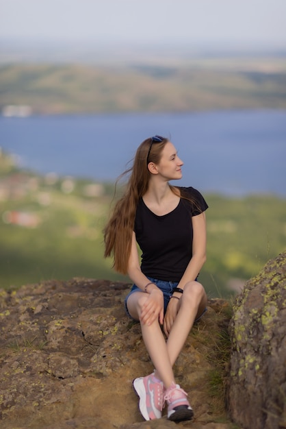 Randonneuse avec sac à dos assise au sommet de la montagne, profitant de la vue pendant la journée.