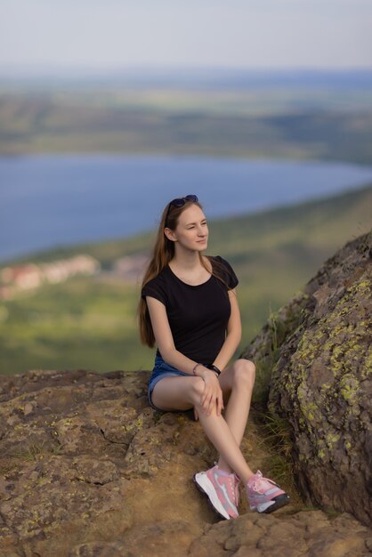 Randonneuse avec sac à dos assise au sommet de la montagne, profitant de la vue pendant la journée.