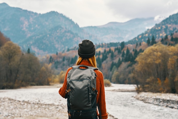 Une randonneuse avec un sac à dos se repose dans les montagnes dans la nature près de la rivière