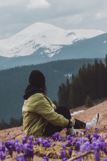 Photo une randonneuse se repose sur une prairie de montagne avec du safran en fleurs les carpates enneigées sont en arrière-plan