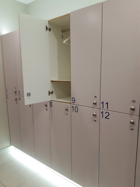 Une rangée d'armoires fermées numérotées dans le vestiaire des sports. L'un d'eux est ouvert et montre un cintre vide.