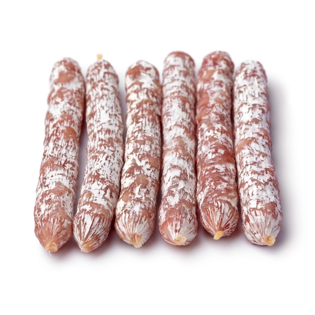 Photo rangée de bâtonnets de salami fumé à sec se bouchent pour une collation sur fond blanc