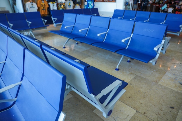 Une rangée de chaises bleues dans un terminal avec un panneau indiquant "aéroport"