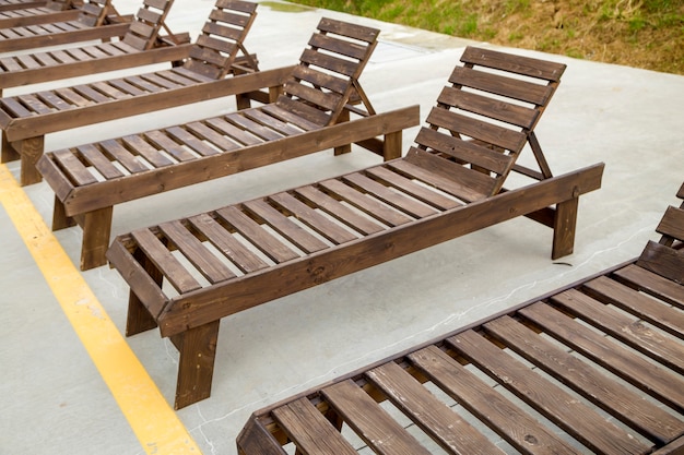 Rangée de chaises de plage en bois vides près de l'eau à l'extérieur.