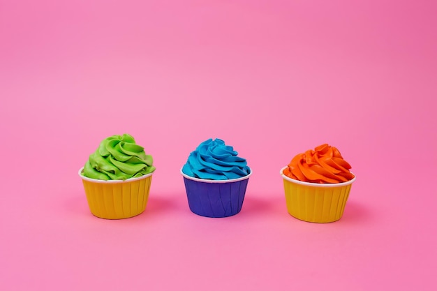 Une rangée de cupcakes colorés sur fond rose