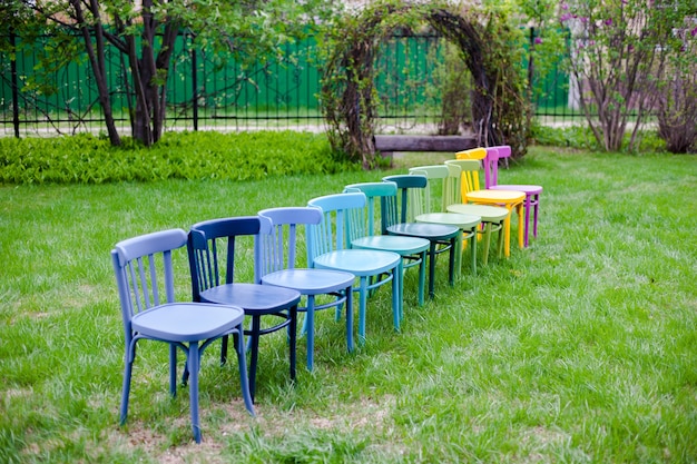 Une Rangée Diagonale De Chaises En Bois Arc-en-ciel Sur Une Pelouse Verte Dans Le Parc Se Préparant à Une Fête De Famille Le ...