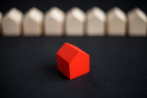 Rangée de maisons en bois avec une seule maison en bois rouge sur fond sombre. Maison en bois rouge debout