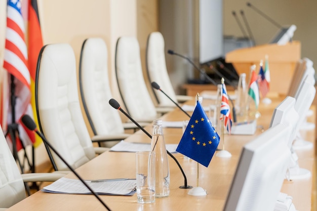 Rangée de microphones drapeaux papiers et autres sur une longue table dans la salle de conférence