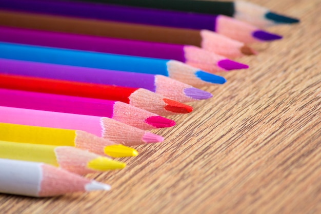 Rangée de nombreux crayons à dessin colorés sur fond de table en bois