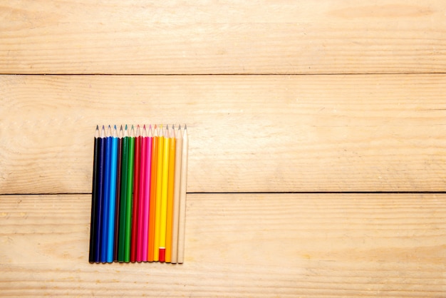 Rangée de papeterie colorée de crayons pour dessiner sur la table en bois