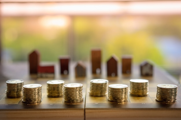 Rangée de pièces de monnaie sur les échecs large avec flou fond de modèle de maison en bois, marché immobilier