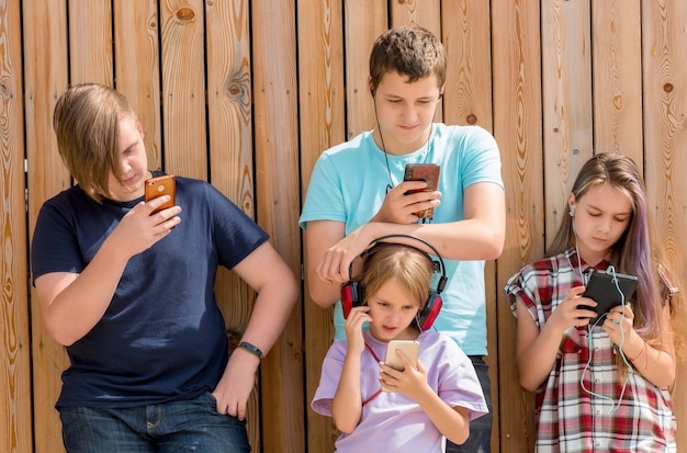 Rangée de quatre amis utilisant des téléphones portables. Concept d'enfants et de gadgets.