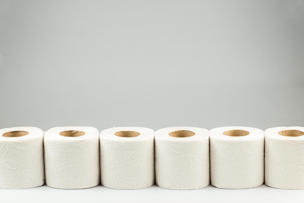 Une rangée de rouleaux de papier toilette sur fond gris