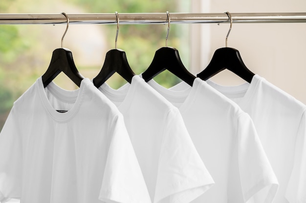 Photo rangée de t-shirts blancs sur des cintres sur rack