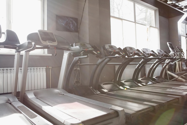 Rangée de tapis roulants vides au soleil à la salle de sport