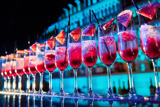 Une rangée de verres avec des tranches de champagne et de pamplemousse sur le comptoir du bar en cours de préparation